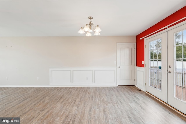 interior space with an inviting chandelier, french doors, and light wood-type flooring