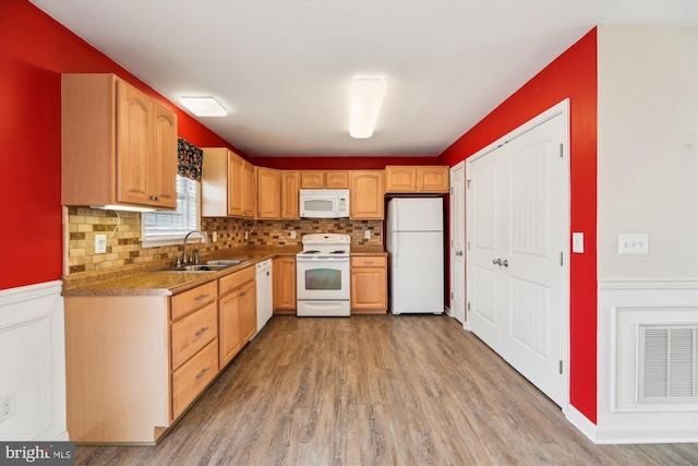 kitchen with sink, white appliances, light hardwood / wood-style floors, and backsplash