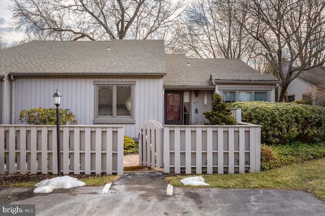 view of front of house with a fenced front yard and roof with shingles