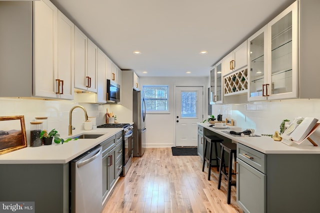 kitchen featuring appliances with stainless steel finishes, gray cabinetry, backsplash, and light hardwood / wood-style flooring