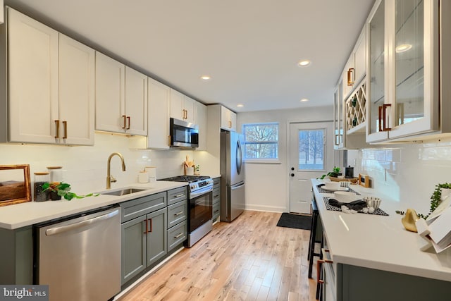 kitchen featuring sink, gray cabinetry, stainless steel appliances, white cabinets, and light wood-type flooring