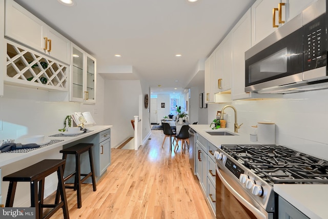 kitchen featuring sink, light hardwood / wood-style floors, white cabinets, and appliances with stainless steel finishes