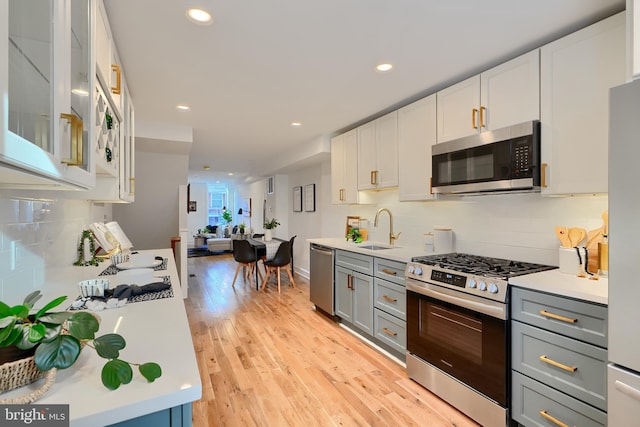 kitchen featuring appliances with stainless steel finishes, sink, gray cabinetry, white cabinets, and backsplash