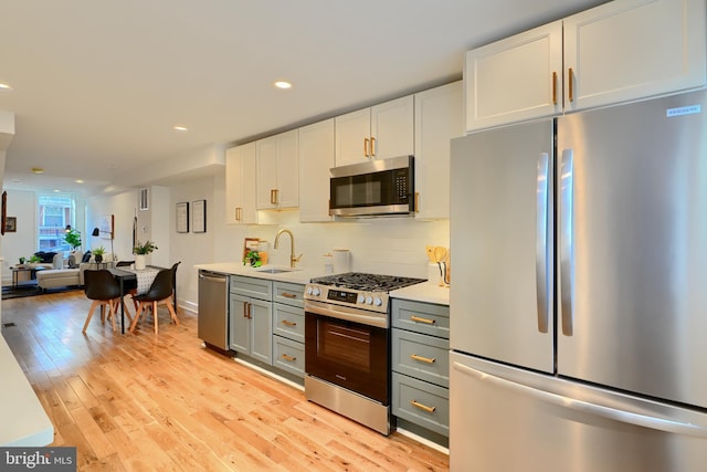 kitchen featuring appliances with stainless steel finishes, sink, gray cabinetry, white cabinets, and backsplash