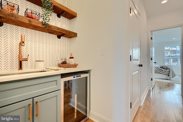 bar featuring sink, beverage cooler, and light hardwood / wood-style floors