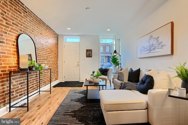 living room with brick wall and light hardwood / wood-style flooring