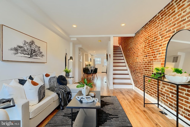 living room featuring brick wall and light hardwood / wood-style flooring