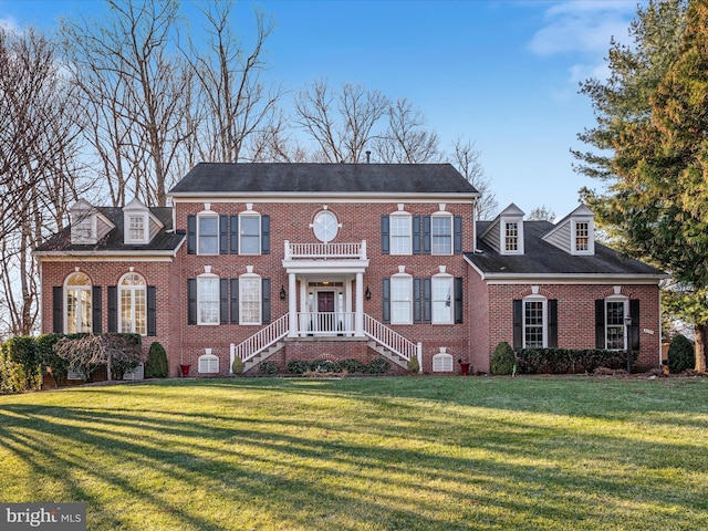 colonial inspired home featuring brick siding and a front yard