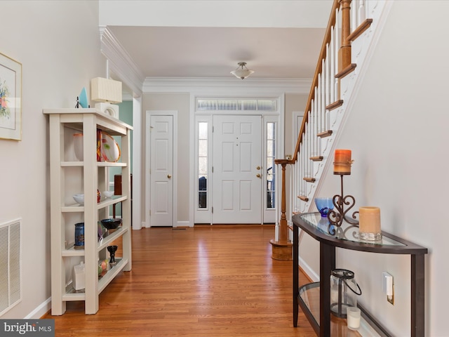 foyer entrance featuring light wood-style flooring, visible vents, baseboards, stairway, and crown molding