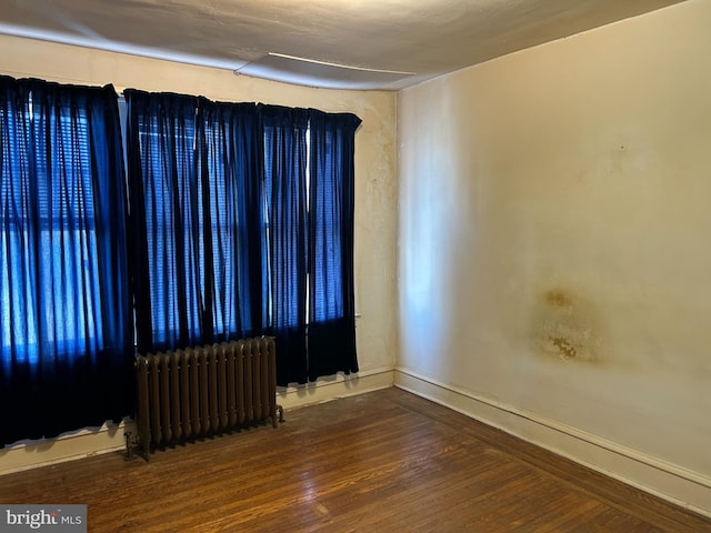 unfurnished room with hardwood / wood-style floors and radiator heating unit