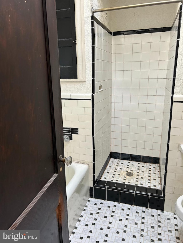 bathroom with tile walls, independent shower and bath, and tile patterned flooring