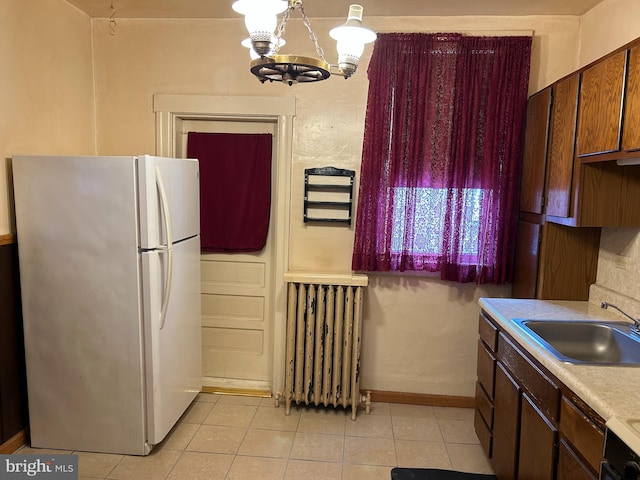 kitchen with radiator heating unit, sink, black range with electric stovetop, an inviting chandelier, and white refrigerator