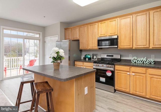 kitchen featuring a kitchen island, appliances with stainless steel finishes, a breakfast bar area, and light hardwood / wood-style flooring