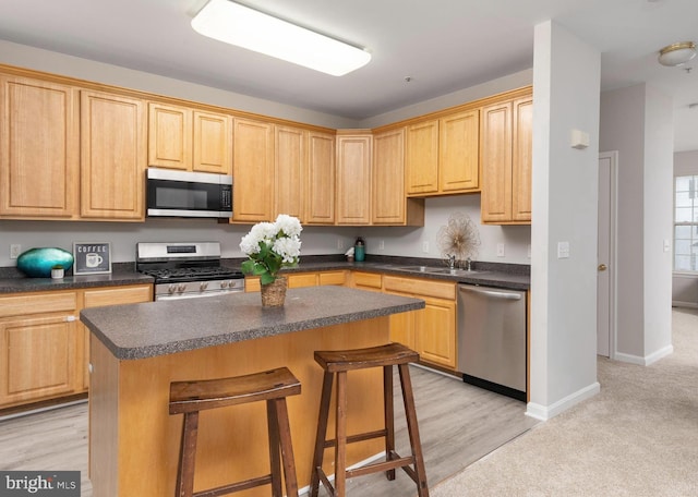 kitchen with stainless steel appliances, a center island, and light brown cabinetry