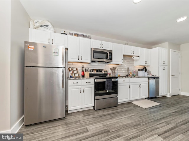 kitchen featuring backsplash, white cabinetry, light hardwood / wood-style floors, and stainless steel appliances