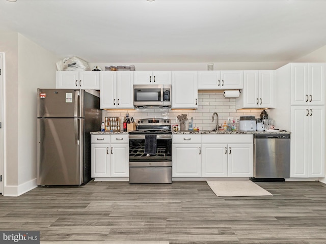 kitchen featuring white cabinets, appliances with stainless steel finishes, sink, backsplash, and dark hardwood / wood-style floors