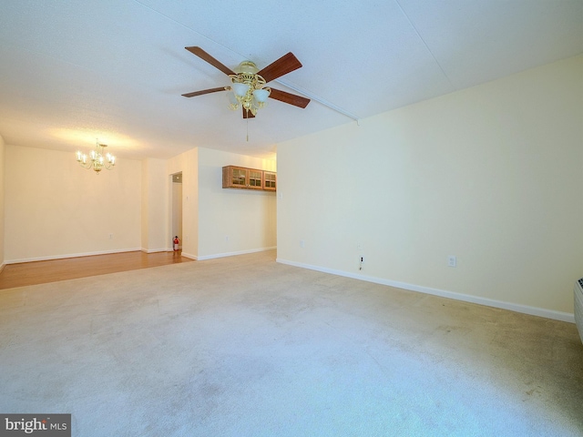 carpeted spare room featuring a textured ceiling and ceiling fan with notable chandelier