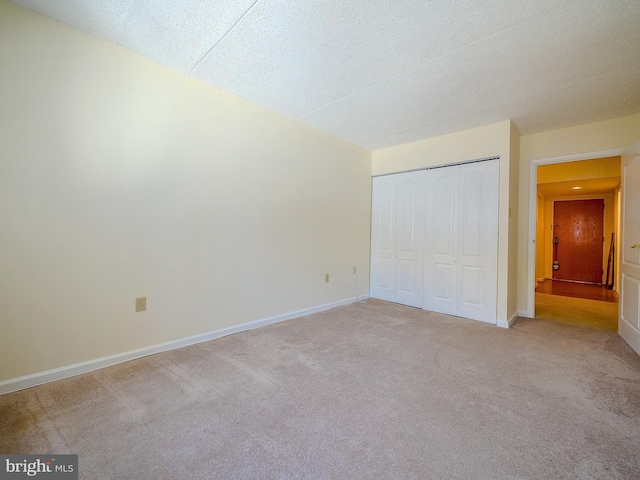 unfurnished bedroom with light carpet, a textured ceiling, and a closet