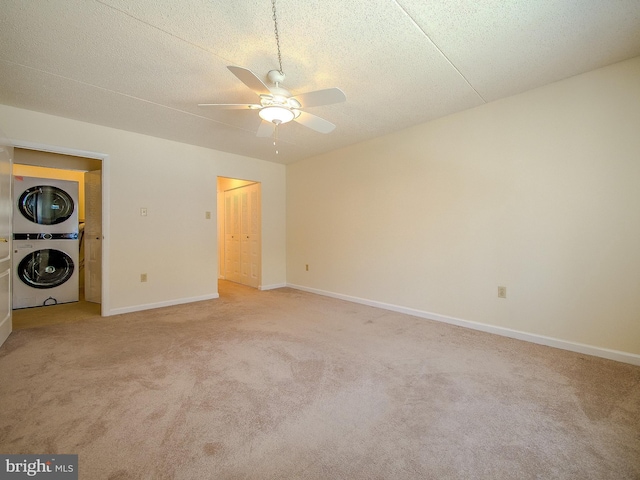 interior space with ceiling fan, light colored carpet, a textured ceiling, and stacked washer and dryer