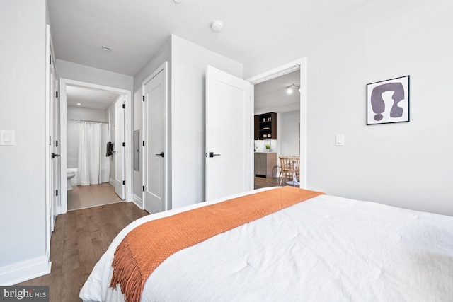 bedroom featuring ensuite bathroom and dark hardwood / wood-style flooring