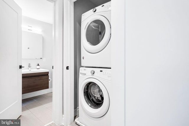 clothes washing area featuring sink, stacked washer / drying machine, and light tile patterned flooring