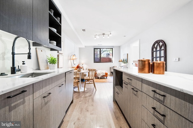 kitchen featuring sink, light hardwood / wood-style floors, and light stone countertops