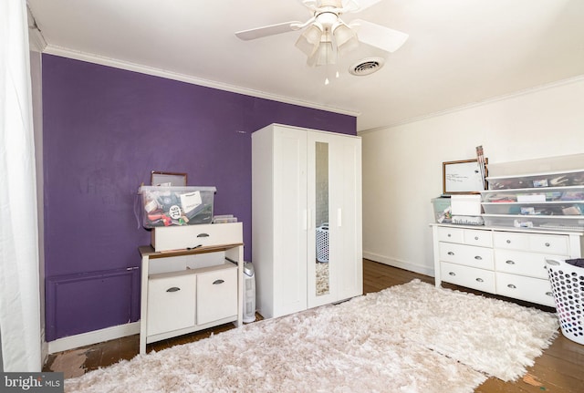 bedroom featuring dark hardwood / wood-style flooring, ornamental molding, and ceiling fan