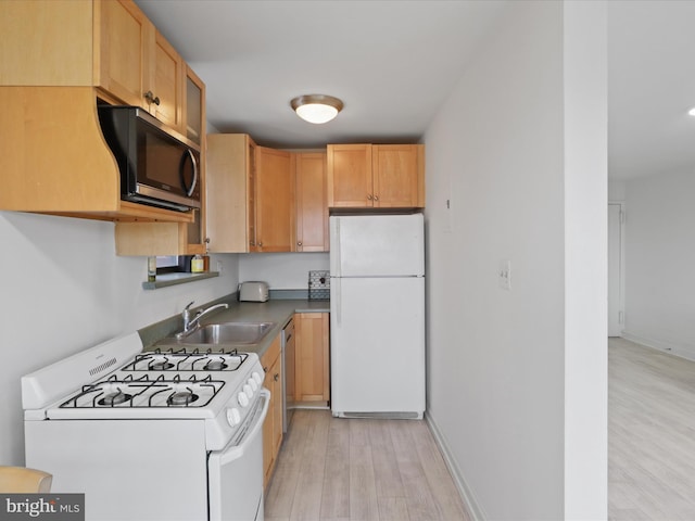 kitchen featuring appliances with stainless steel finishes, sink, light brown cabinets, and light wood-type flooring