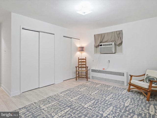 living area featuring cooling unit, radiator heating unit, and light hardwood / wood-style flooring