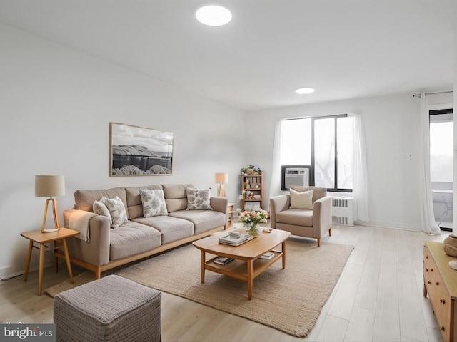 living room with cooling unit, radiator, and light hardwood / wood-style flooring