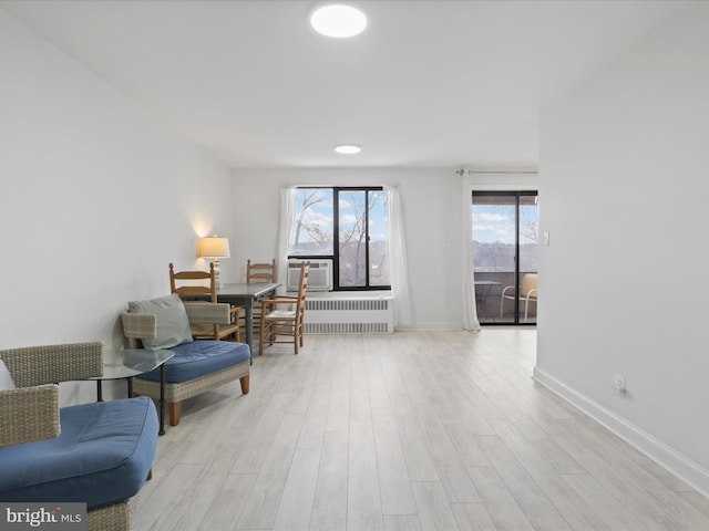 living area with cooling unit, radiator, and light hardwood / wood-style floors