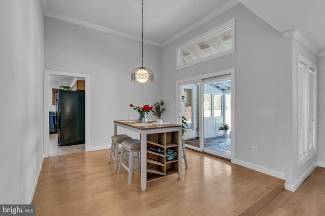 dining space featuring ornamental molding, a towering ceiling, and light wood-type flooring