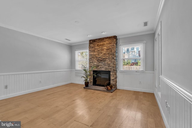 unfurnished living room featuring crown molding, a fireplace, and light hardwood / wood-style floors