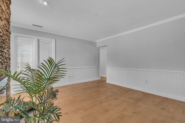 unfurnished room with ornamental molding and light wood-type flooring