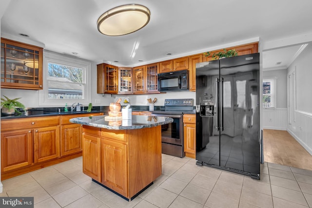 kitchen with light tile patterned flooring, black appliances, and a kitchen island