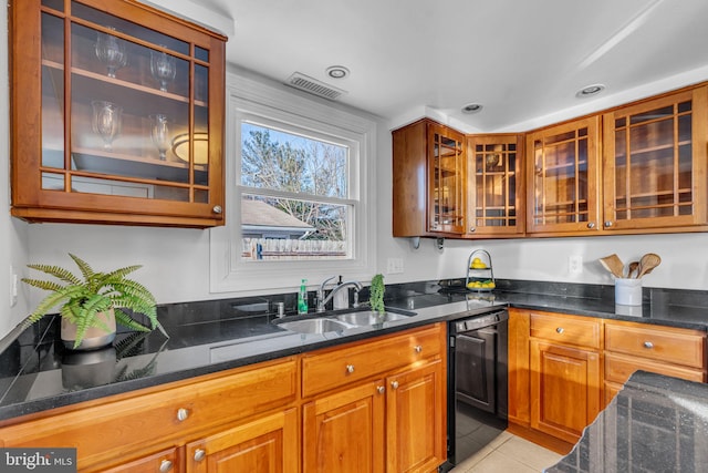 kitchen with black dishwasher, sink, dark stone counters, and light tile patterned floors