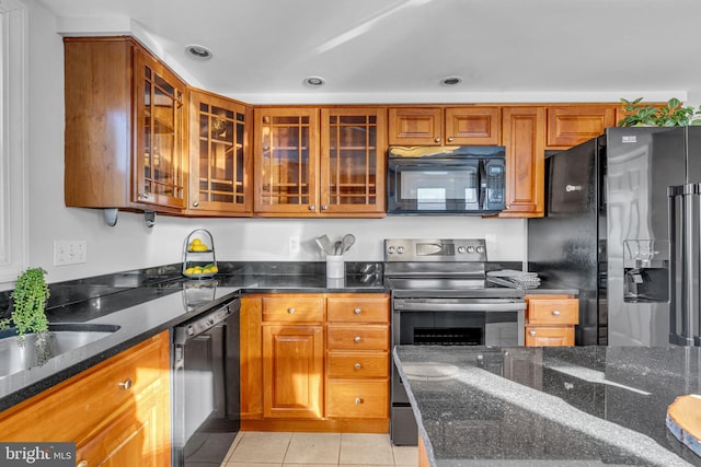 kitchen with light tile patterned flooring, sink, dark stone counters, and black appliances