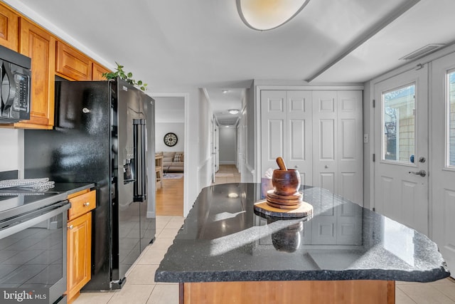 kitchen featuring electric range, dark stone counters, a kitchen island, and light tile patterned floors