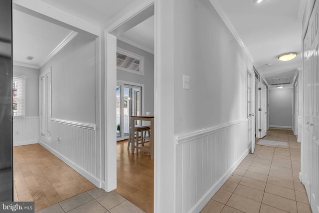 hallway with ornamental molding and light tile patterned floors