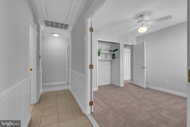 corridor featuring ornamental molding and light tile patterned floors