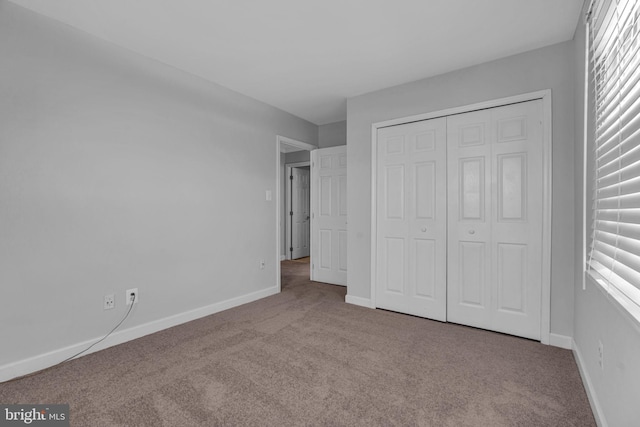 unfurnished bedroom featuring light colored carpet and a closet