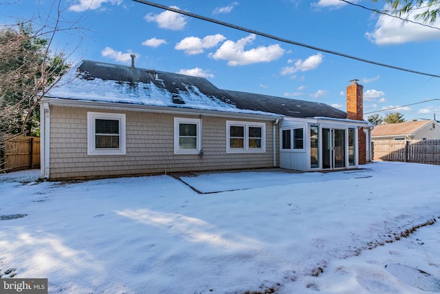 snow covered house featuring a sunroom