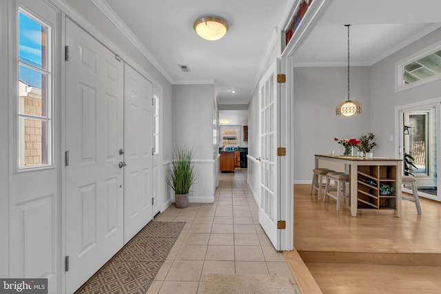 foyer entrance with ornamental molding and light tile patterned floors