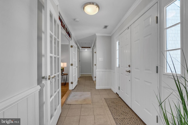 entryway featuring french doors, ornamental molding, a wealth of natural light, and light tile patterned floors