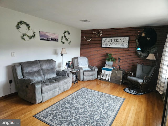 living room featuring brick wall and wood-type flooring