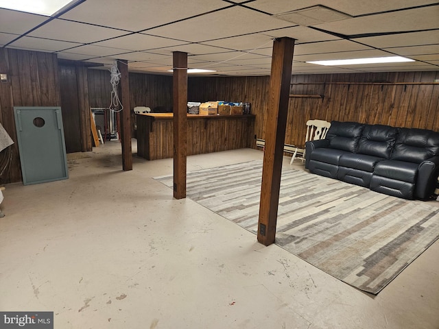 basement featuring a paneled ceiling and wood walls