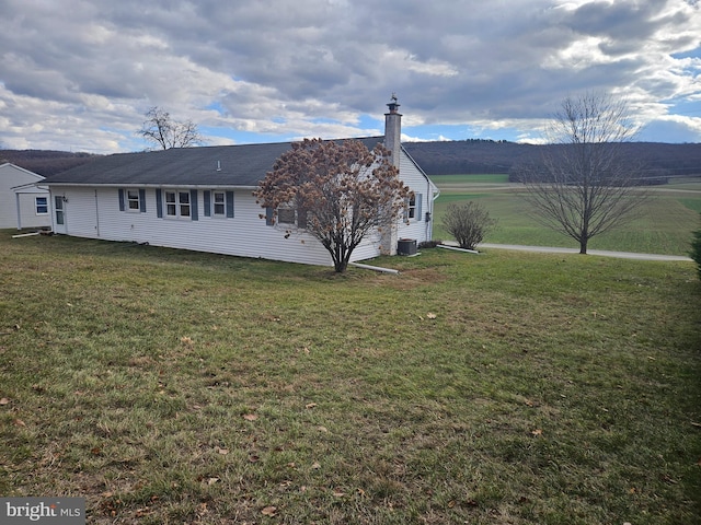 exterior space with central AC, a yard, and a mountain view