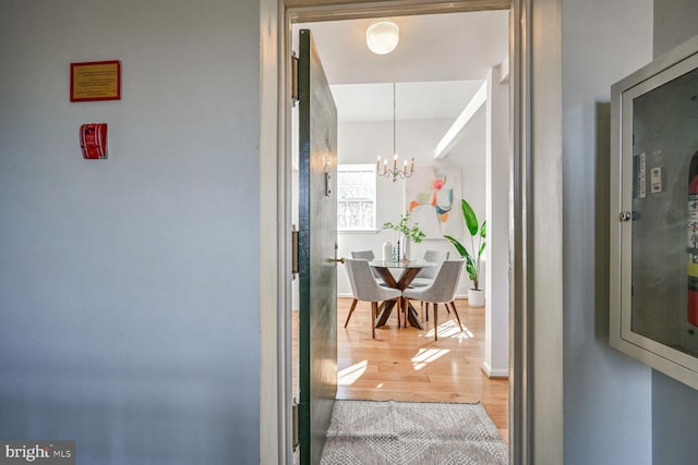 hall with an inviting chandelier and hardwood / wood-style flooring