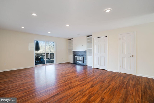 unfurnished living room featuring a brick fireplace, built in features, and dark hardwood / wood-style floors