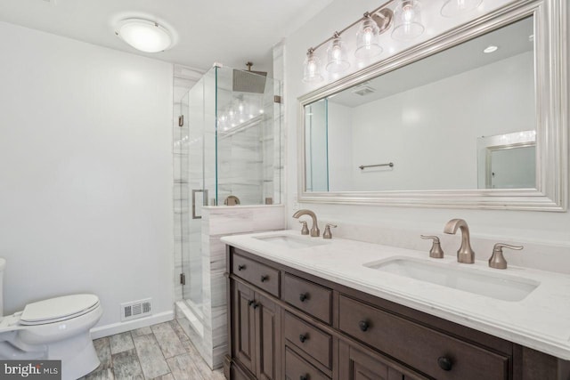 bathroom with vanity, a shower with door, and toilet